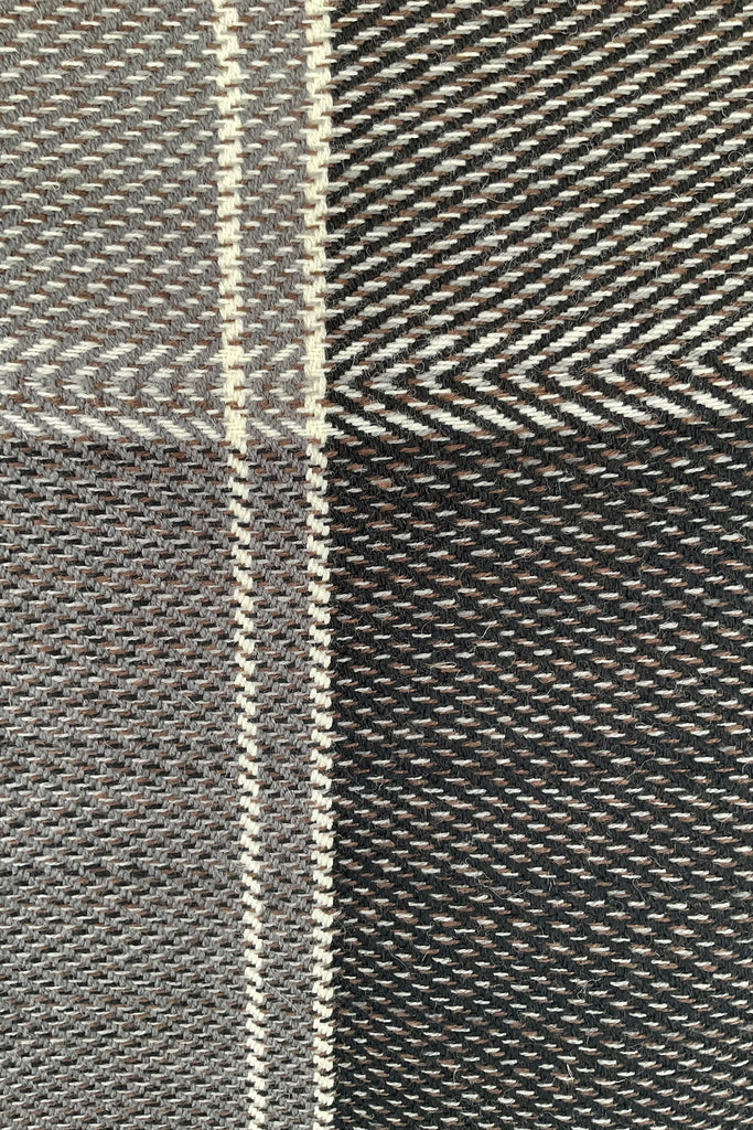 A close up of sepia-toned grey wool plaid cape tartan weave