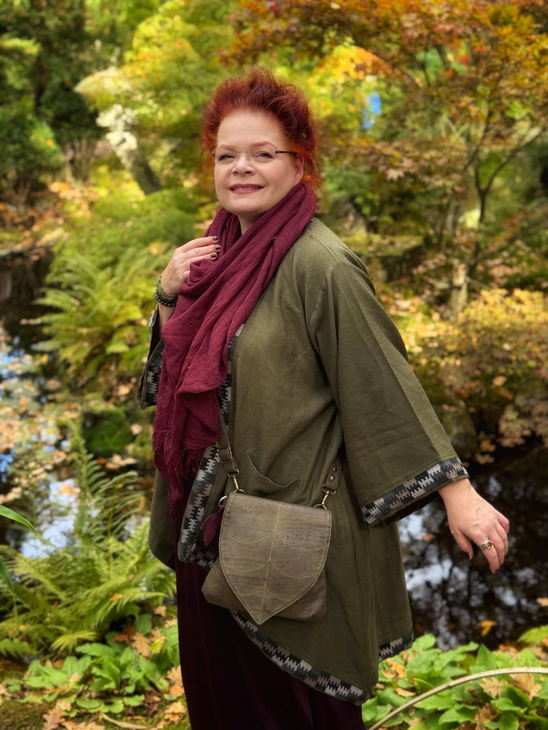 Woman with red hair and glasses standing in a forest setting
