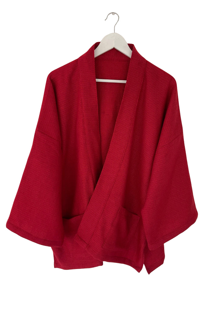 Red wool jacket on a hanger against a white background