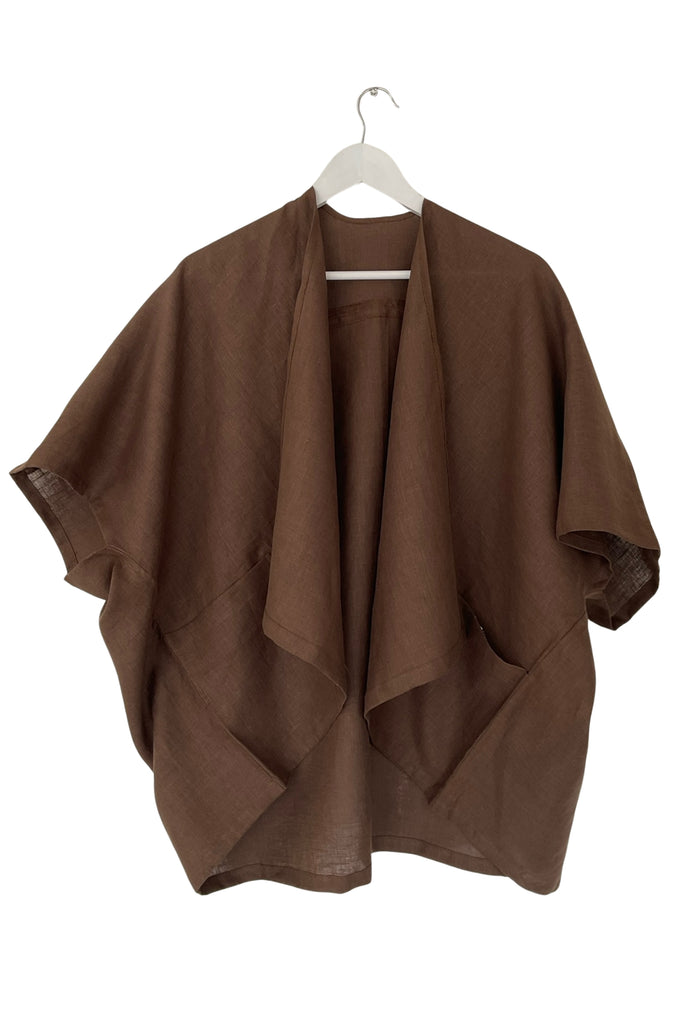Brown poncho on a white hanger against a white background