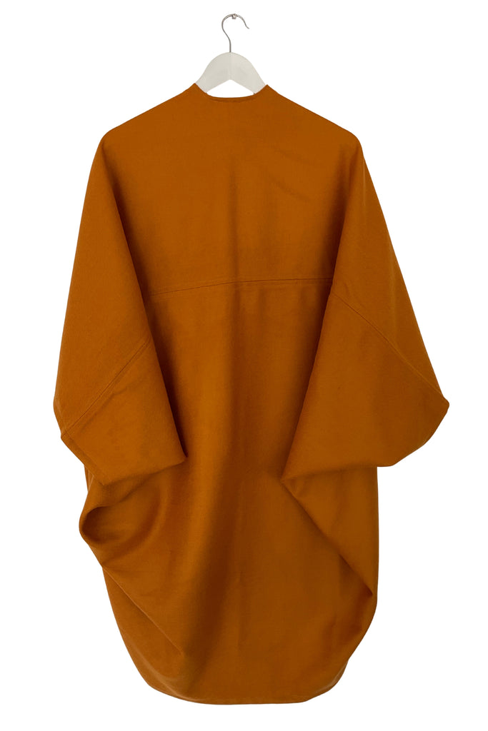 Ochre kimono style garment on a white hanger against a white background
