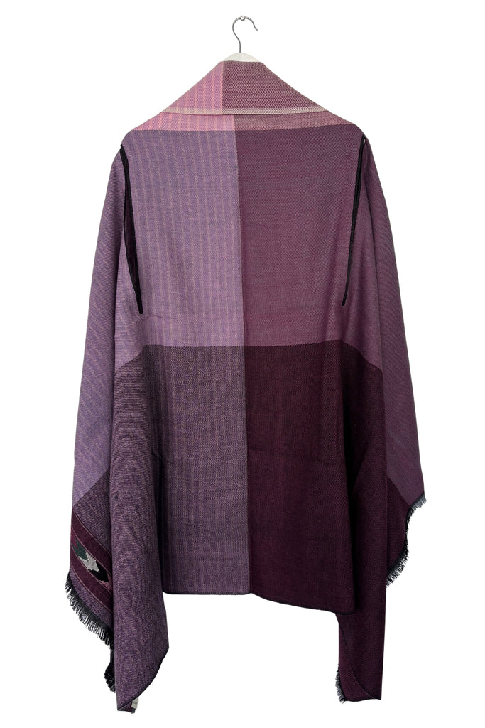 Purple wool cape on a hanger against a white background