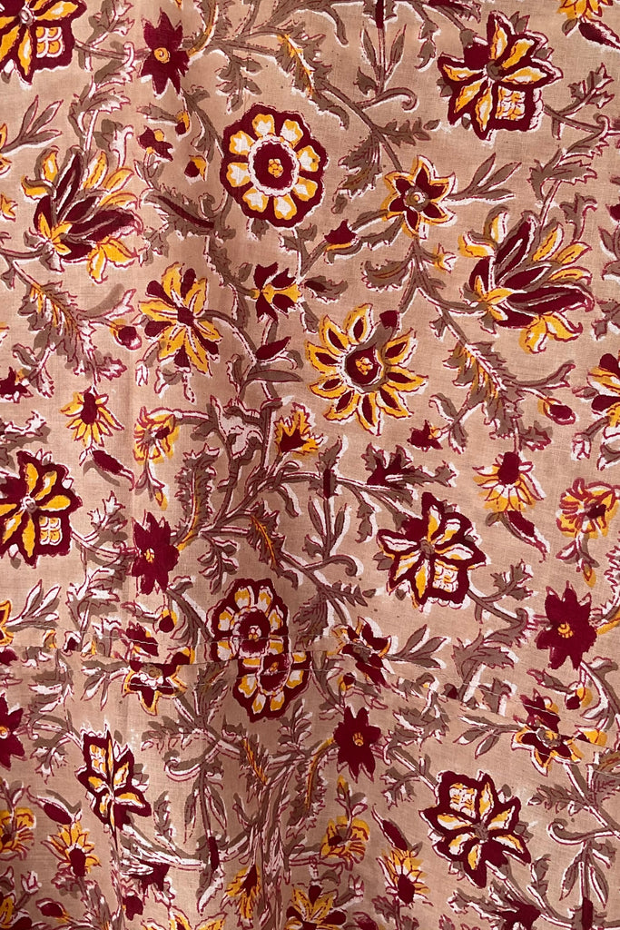 Close-up of a floral patterned fabric with brown and yellow colors on a beige background.