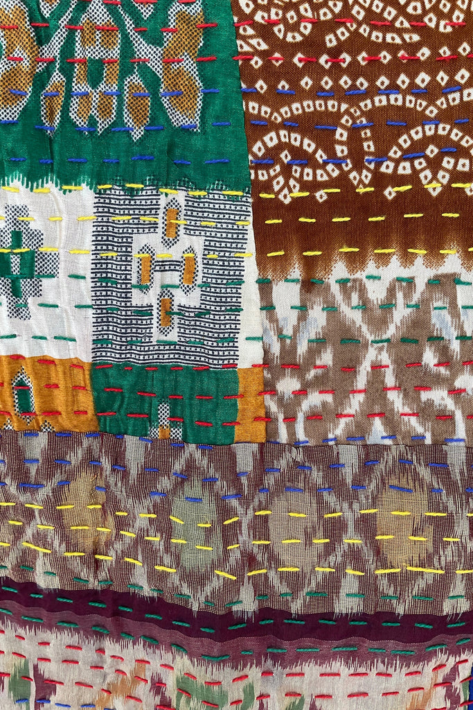 Close-up of a colorful fabric with intricate patterns in green, brown, and multicolor.